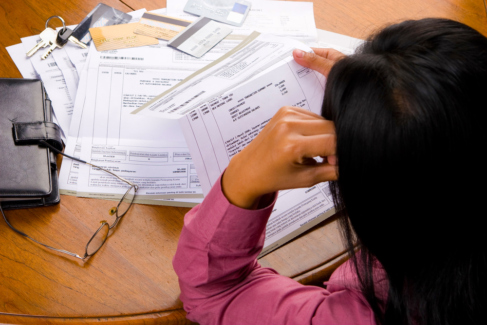 woman looking at a pile of bills on the floor