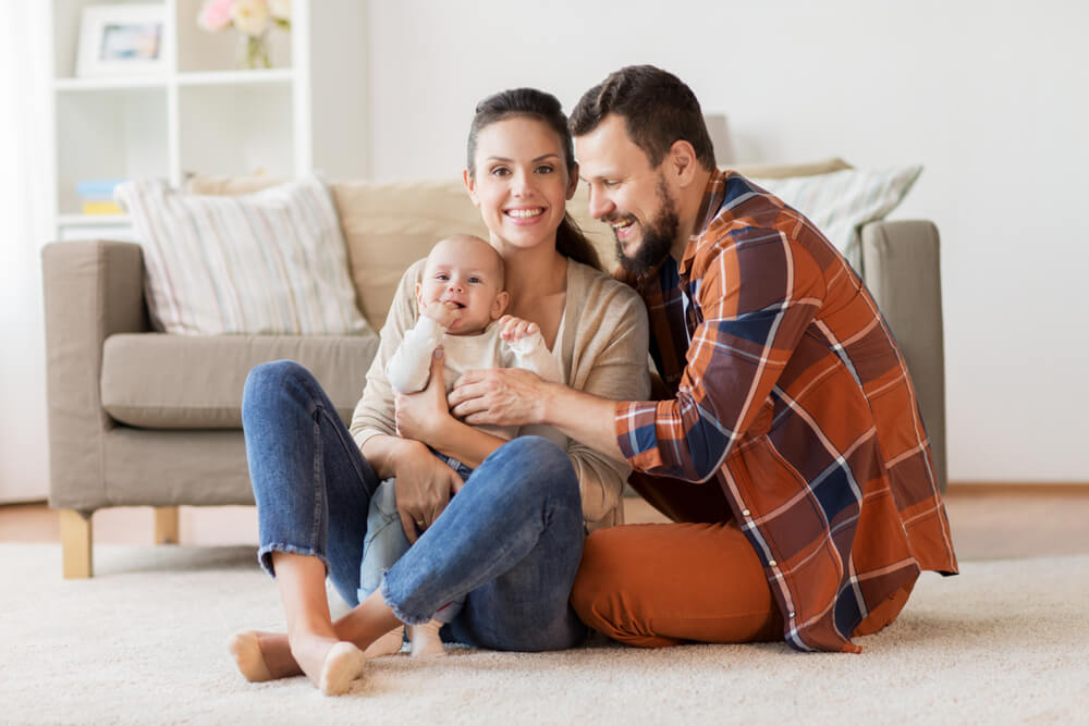 Man and woman sitting on living room floor with their new baby